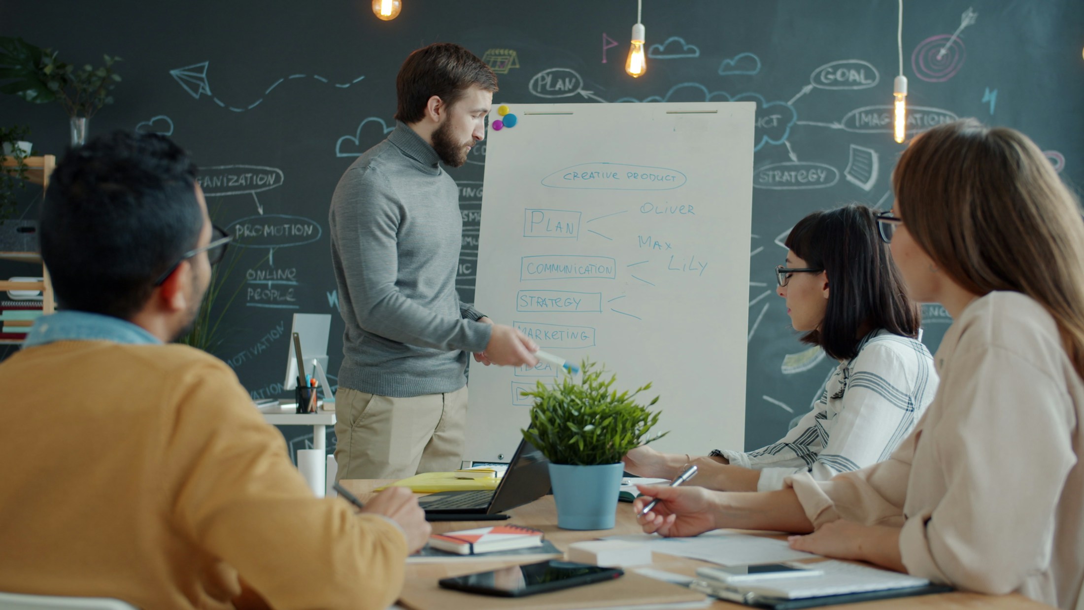 Colleagues brainstorming a project and organizing their ideas at a whiteboard